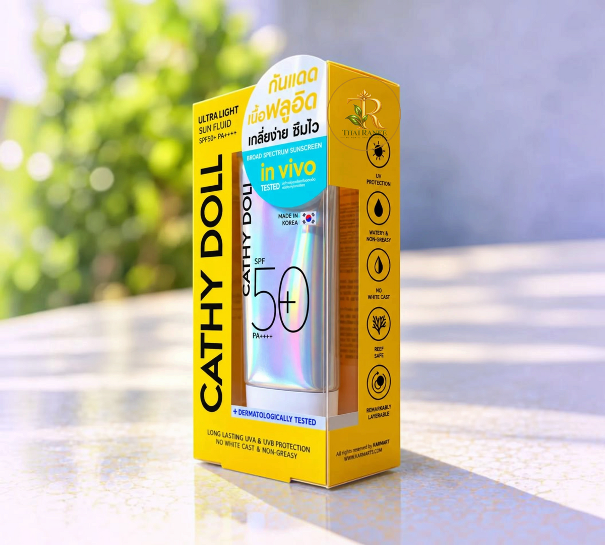 Thai Ranee Cathy Doll Ultra Light Sun Fluid SPF50+ PA++++ sunscreen in yellow retail packaging on a sunny background.