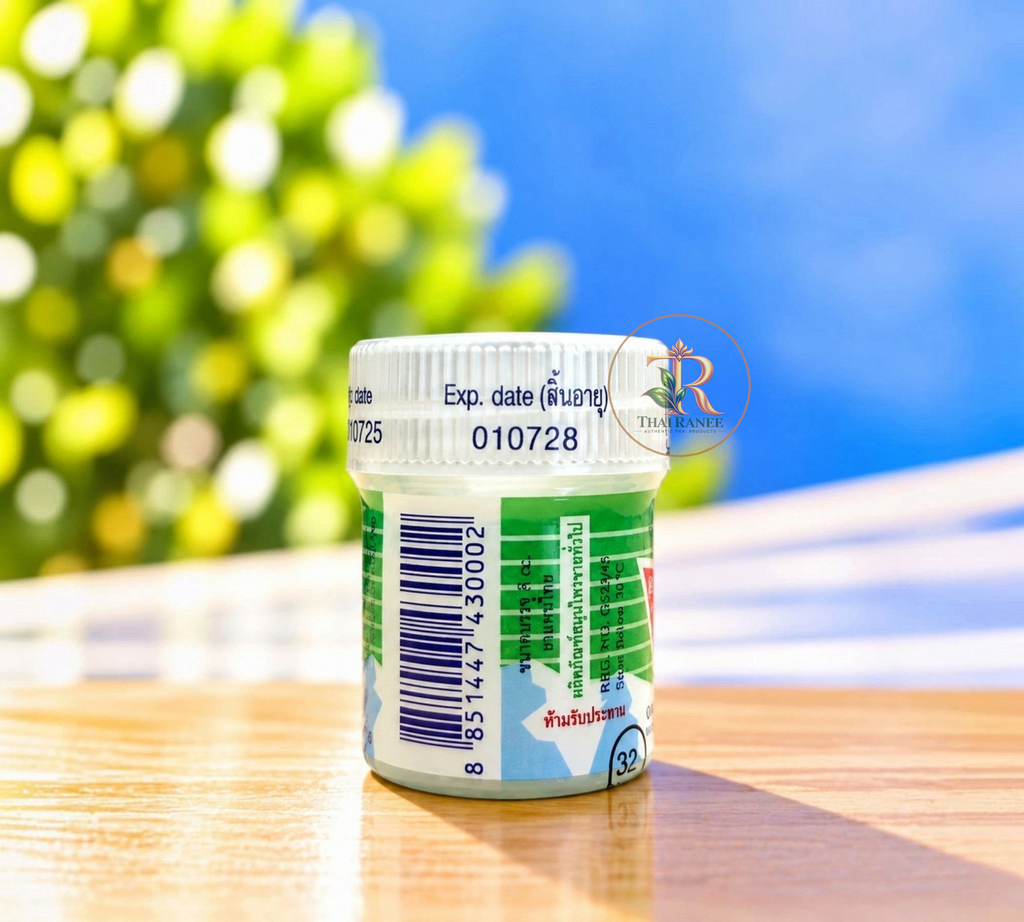 Thai Ranee traditional herbal medicated balm in a compact white jar with expiration date on a wooden surface