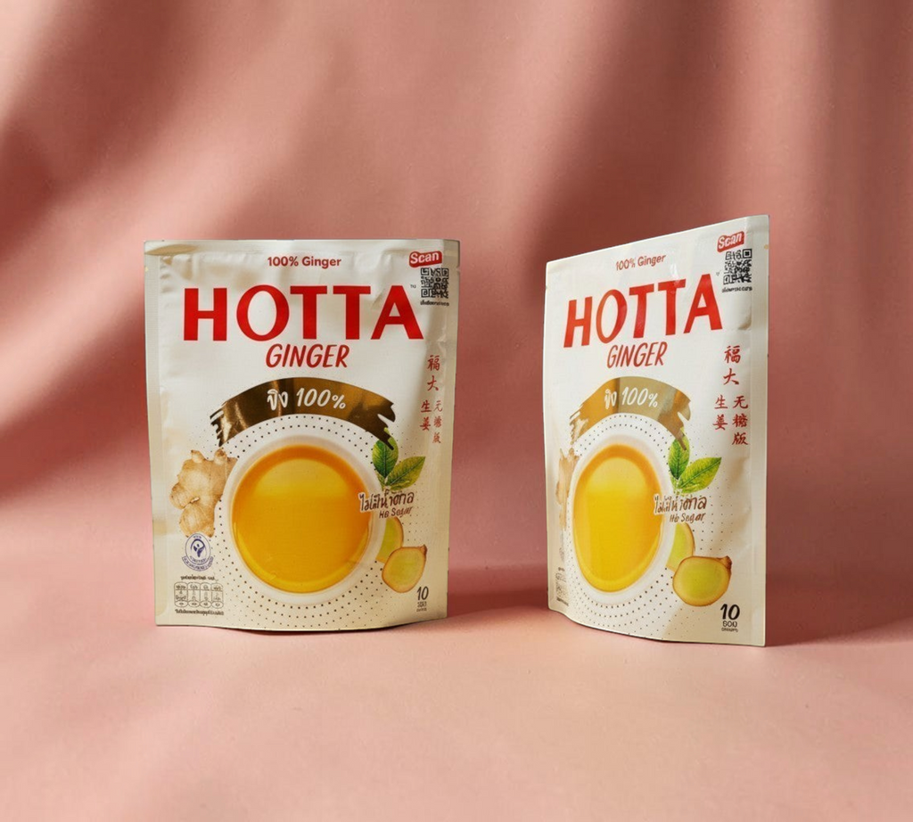 Thai Ranee HOTTA 100% sugar-free instant ginger beverage sachets in white packaging on a warm yellow background.