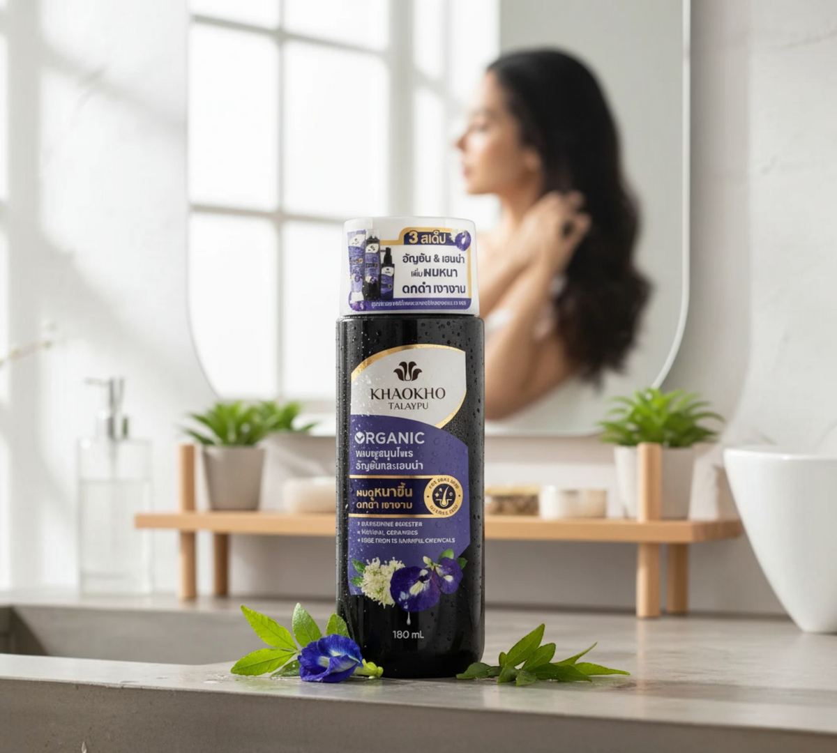 Thai Ranee Khaokho Talaypu organic butterfly pea and henna shampoo bottle on a bathroom counter with fresh flowers.